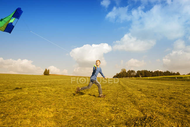 Мальчик запускает воздушного змея на лугу — стоковое фото