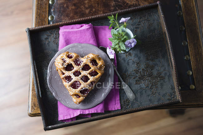 Herzförmige Kirschtorte und Blumen auf Tablett — Stockfoto