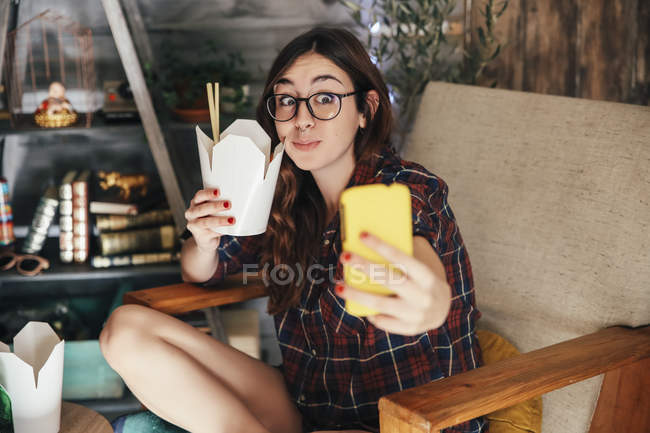 Young woman taking a selfie with her Chinese takeaway — Stock Photo