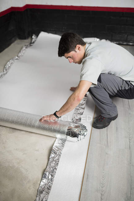 Young man placing a insulating material for a laminate flooring — Stock Photo