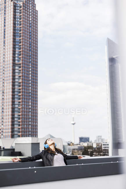 Giovane donna in città indossando le cuffie, ascoltando musica — Foto stock