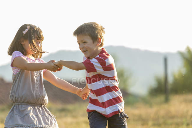 Счастливые мальчик и девочка, играющие вместе на природе — стоковое фото