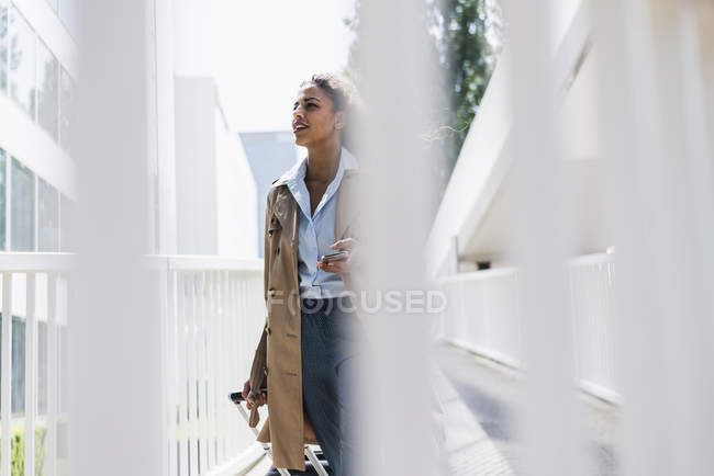 Junge Frau mit Gepäck und Handy unterwegs — Stockfoto