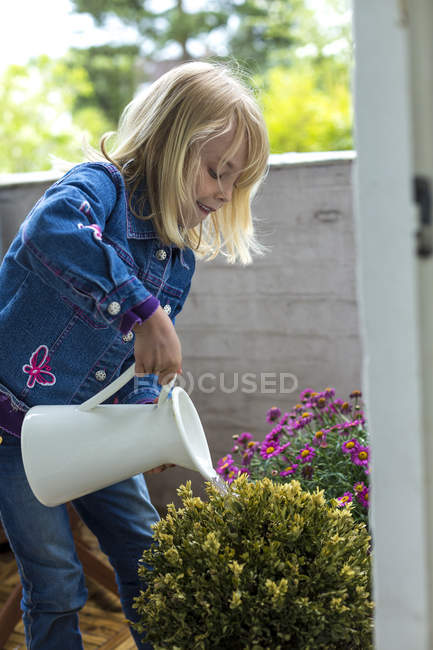 Girl watering plants on balcony — Stock Photo