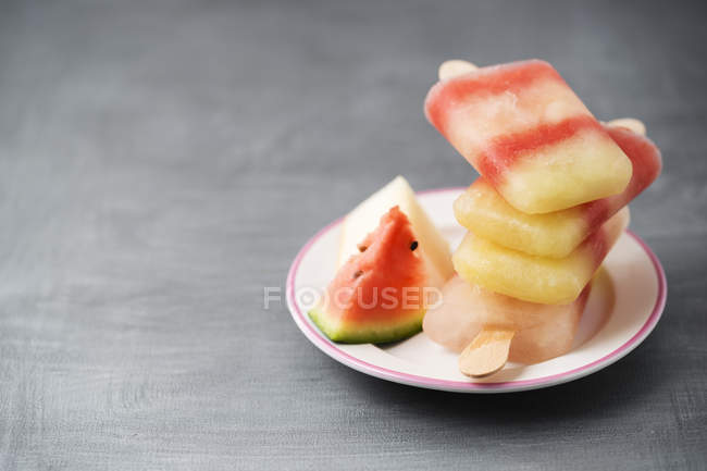 Piatto con pila di diversi lecca-lecca al melone fatti in casa — Foto stock