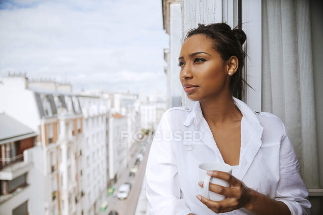 France, Paris, portrait d'une jeune femme avec une tasse de café regardant loin — Photo de stock