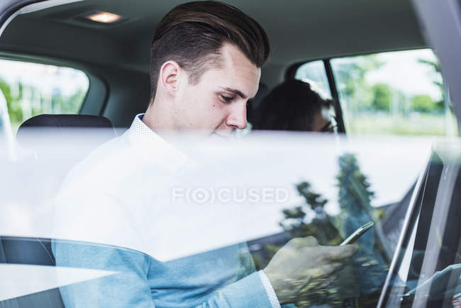 Junger Mann mit Handy und Frau im Auto — Stockfoto