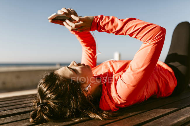 Femme se reposant et utilisant le téléphone après avoir couru — Photo de stock