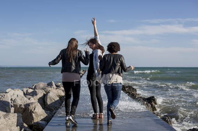 Drei junge Frauen amüsieren sich auf Wellenbrecher am Meer — Stockfoto