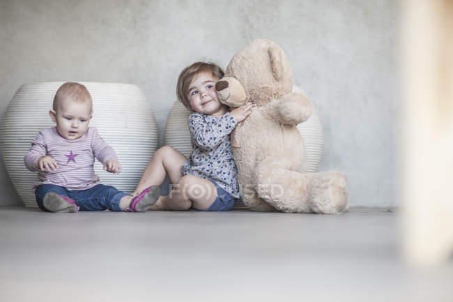 Дві дівчинки і плюшевий ведмідь вдома — стокове фото