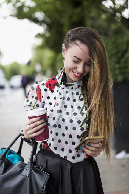 Smiling woman with coffee and smartphone — Stock Photo