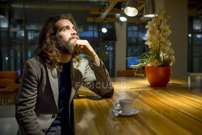 Молодой бизнесмен-хипстер сидит за чашкой кофе в кафетерии — стоковое фото