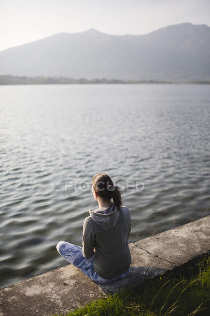 Italia, Lecco, giovane donna rilassata seduta sulla riva del lago — Foto stock