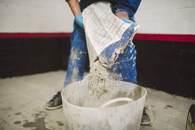 Bricklayer pouring cement powder in bucket — Stock Photo