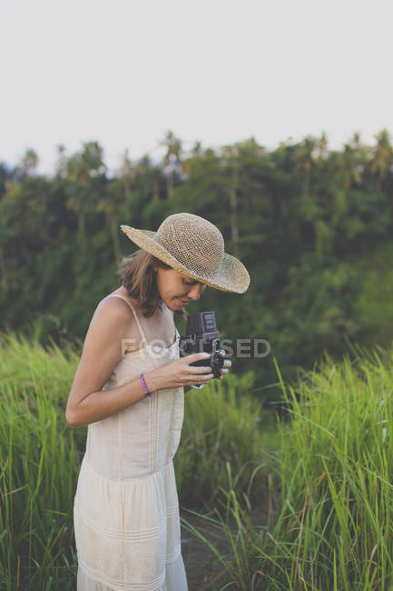 Улыбающаяся женщина с ретро камерой в природе — стоковое фото