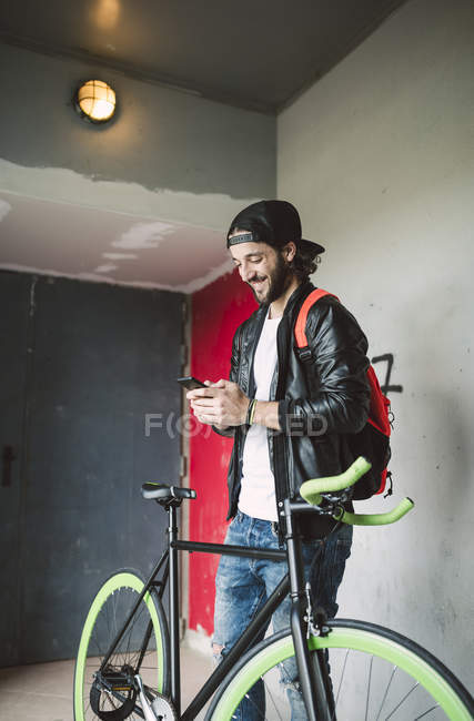 Young man with bicycle looking at smartphone — Stock Photo