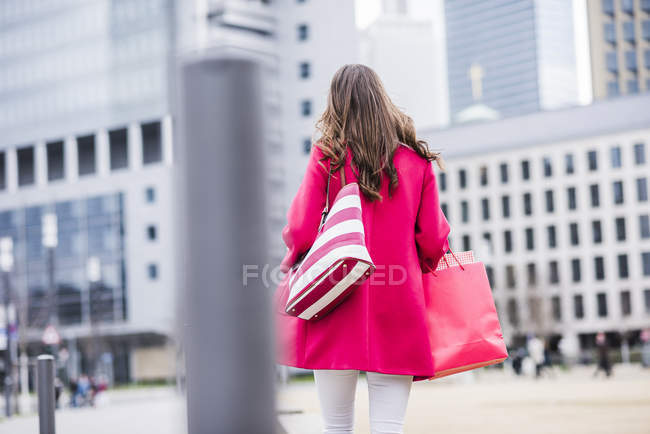Jovem com sacos de compras andando na cidade, vista traseira — Fotografia de Stock