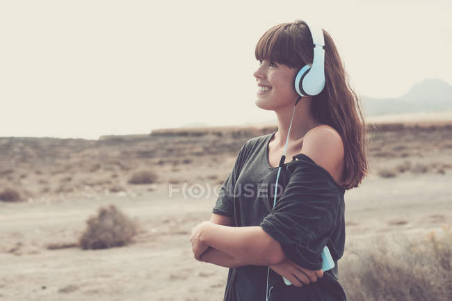 Giovane donna che ascolta musica, sorridendo felicemente — Foto stock