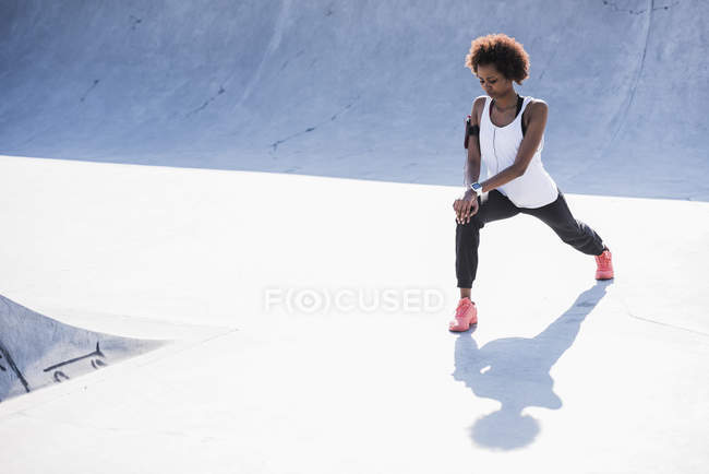 Jovem mulher se alongando no skatepark — Fotografia de Stock
