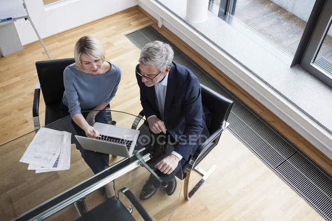 Empresário e empresária usando laptop no escritório — Fotografia de Stock