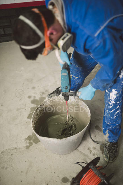 Bricklayer mixing cement in bucket on construction site — Stock Photo