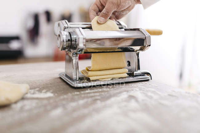 Chef rolling dough with pasta machine — Stock Photo