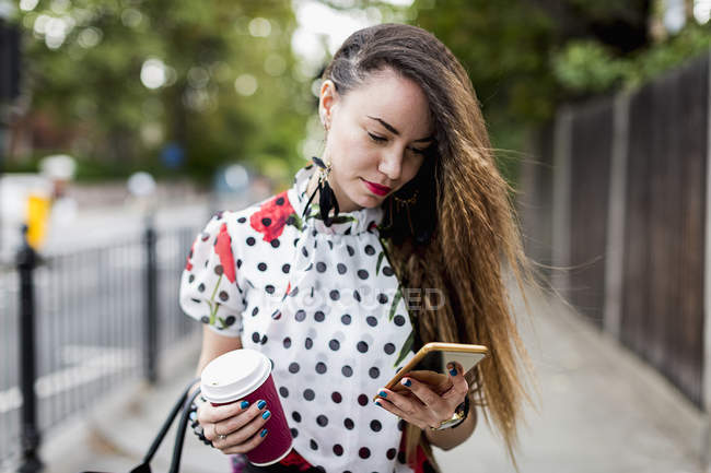 Femme avec café regardant smartphone — Photo de stock