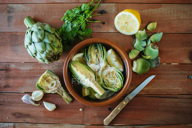 Clay pot of sliced artichokes in water — Stock Photo