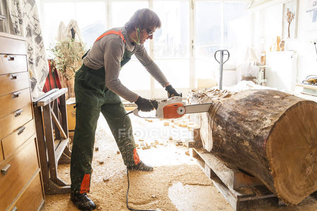 Holzschnitzer in der Werkstatt bearbeitet Holz für eine Skulptur mit der Kettensäge — Stockfoto