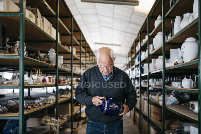 Пожилой человек рассматривает керамическую деталь — стоковое фото