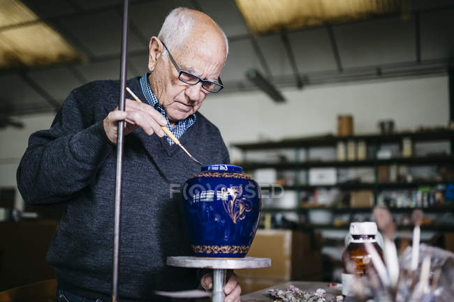 Senior man decorating ceramic vase in his spare time — Stock Photo