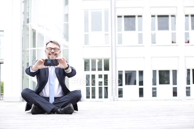 Businessman sitting on ground outdoors — Stock Photo