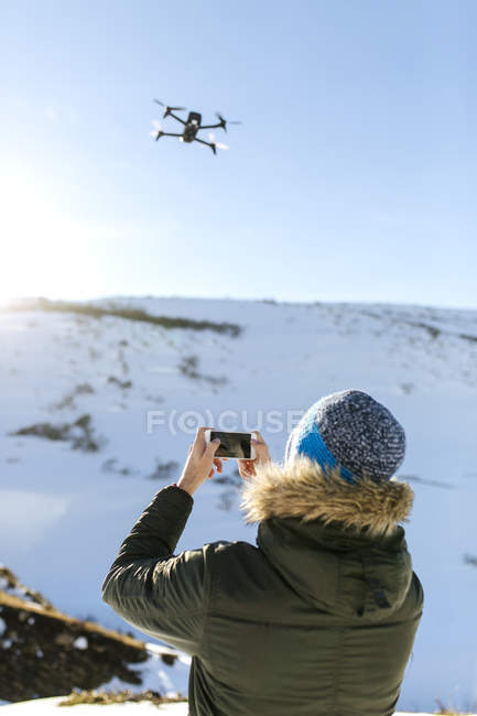 Uomo con drone volante in montagne innevate — Foto stock