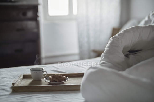 Wooden tray with coffee and biscuits on bed — Stock Photo