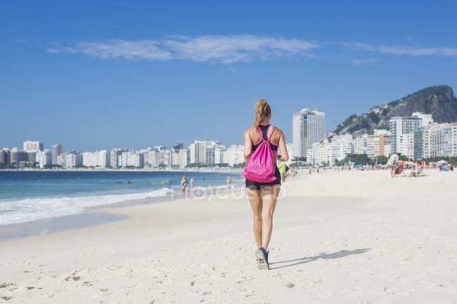 Vista posteriore della donna che fa jogging sulla spiaggia — Foto stock