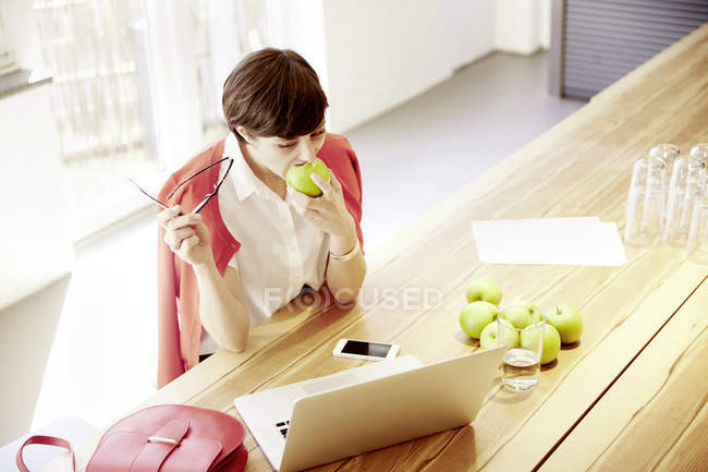 Frau in einer modernen Kantine isst einen Apfel — Stockfoto