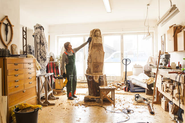 Sculpteur en bois en atelier travaillant sur la sculpture — Photo de stock