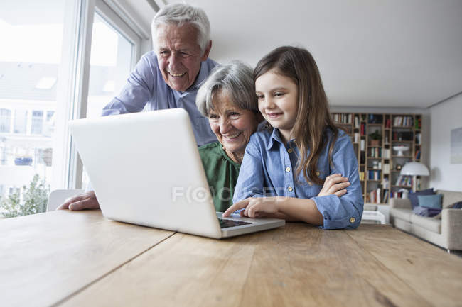 Großeltern und ihre Enkelin mit Laptop zu Hause — Stockfoto
