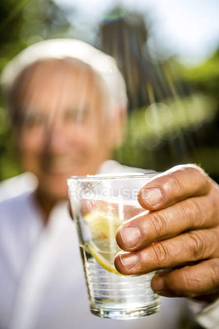 Primo piano dell'uomo anziano che tiene un bicchiere d'acqua — Foto stock