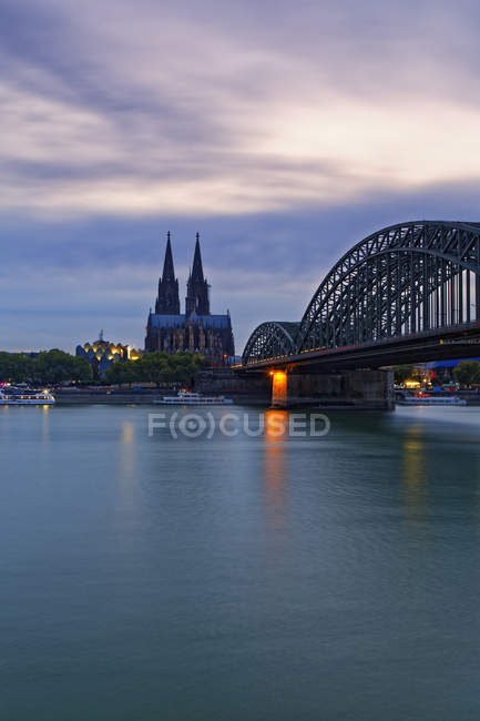 Deutschland, Köln, Blick auf den Kölner Dom mit Hohenzollernbrücke im Vordergrund in der Abenddämmerung — Stockfoto