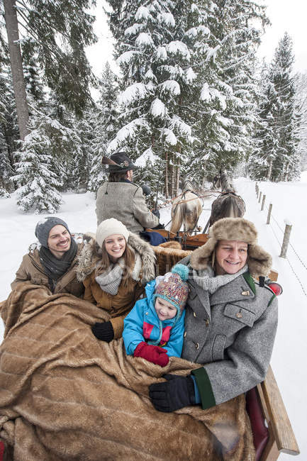 Сім'я, насолоджуючись прокотитися на санях, запряжених взимку — стокове фото