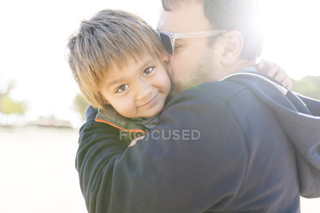 Маленький хлопчик на батьків зброї дивитися через плече — стокове фото