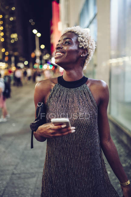 Heureuse femme afro-américaine avec téléphone portable sur Times Square la nuit, NY, USA — Photo de stock