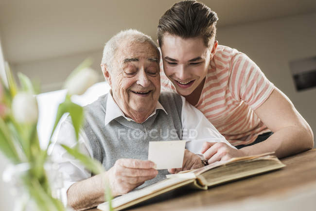 Grandfather and grandson watching old photographies together — Stock Photo