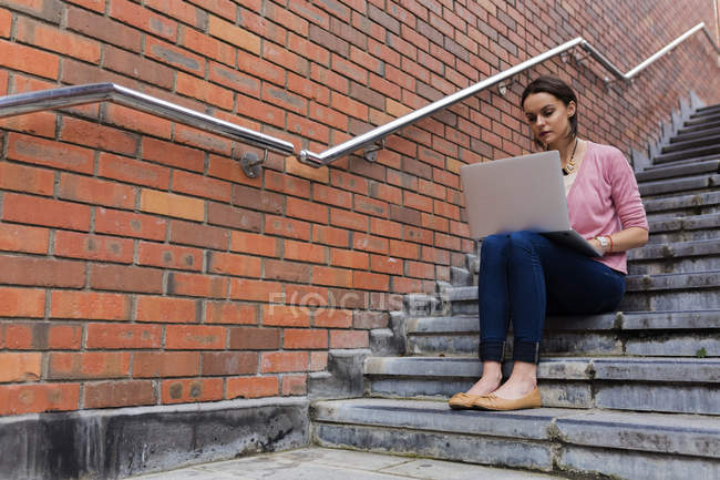 Jeune fille décontractée en utilisant un ordinateur portable sur les escaliers — Photo de stock