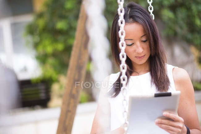 Молода жінка на гойдалки, використовуючи цифровий планшетний — стокове фото