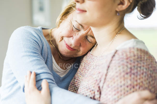 Senior woman with closed eyes leaning on granddaughter shoulder — Stock Photo