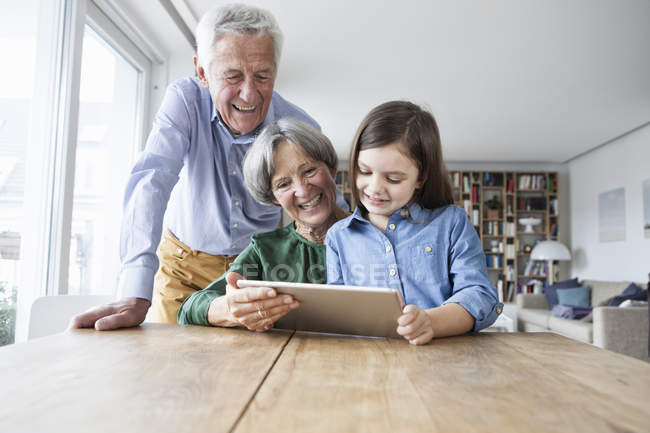 Großeltern und Enkelin mit digitalem Tablet zu Hause — Stockfoto