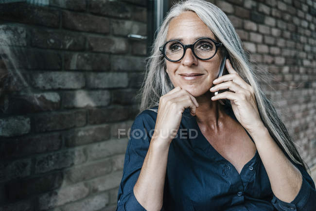 Femme souriante aux longs cheveux gris sur téléphone portable — Photo de stock