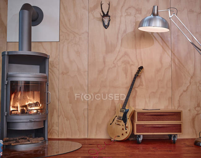 Electric guitar leaning on chest of drawers near fireplace — Stock Photo